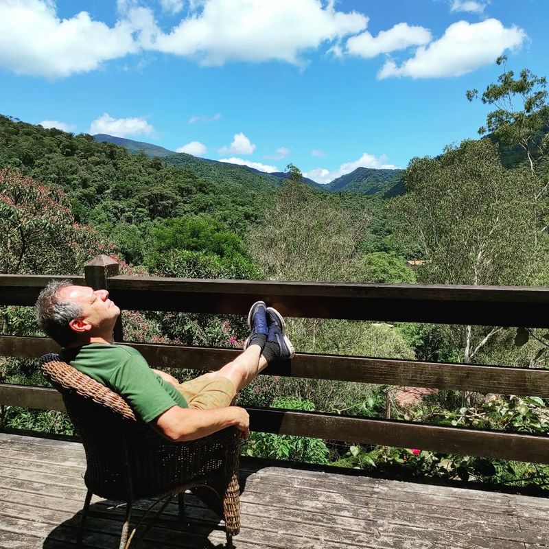 Hóspede descansando no deck, de frente para a serra